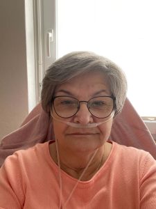 Porträt von Ulrike. Sie trägt eine Sauerstoff-Nasenbrille und blickt in die Kamera.